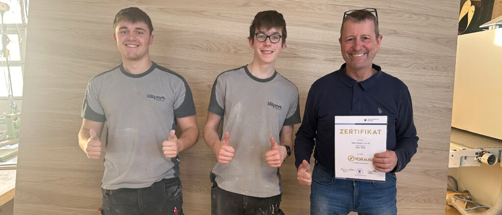 Schreinermeister Johannes Hilpert mit VORAUS-Zertifikat in der Hand zwischen seinen Azubis Anton Genswein und Sebastian Günther.