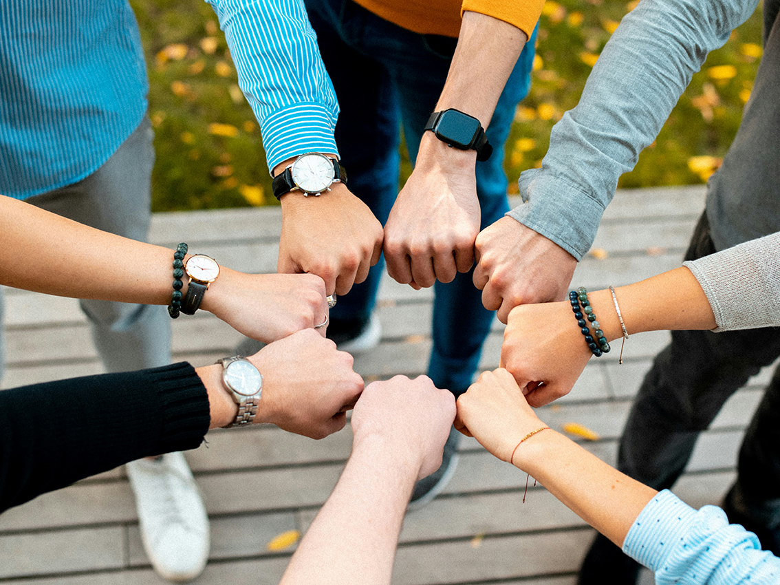 Acht Fäuste unterschiedlicher Menschen bilden einen von oben fotografierten Kreis